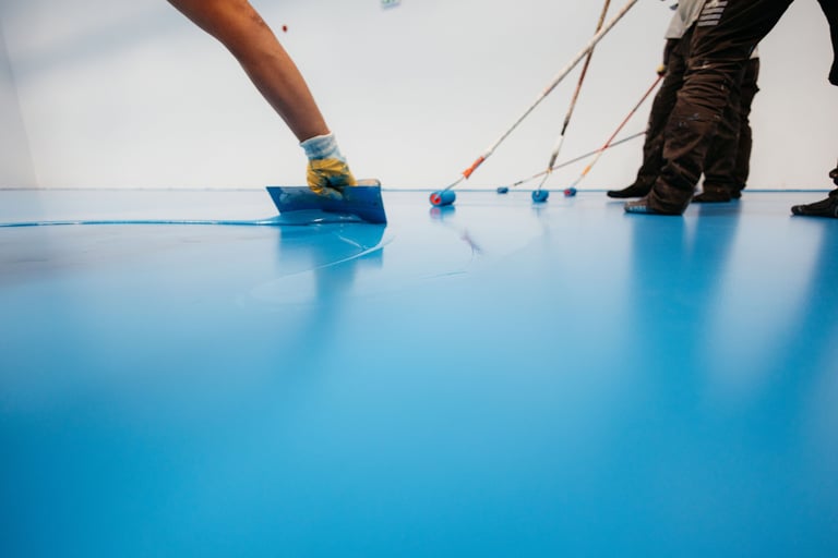Workers applying blue epoxy resin on floor