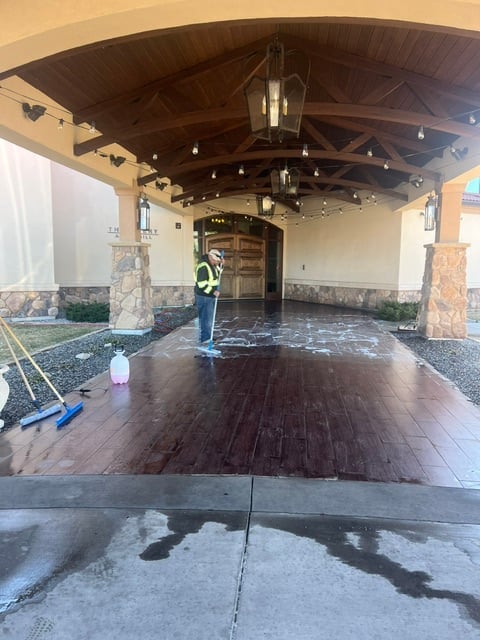 Construction worker in safety vest standing in covered entryway with wooden flooring installation and exposed beam ceiling