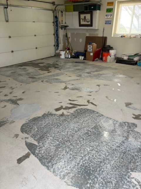 Garage interior with epoxy floor featuring decorative fish design, tool storage, and white garage door