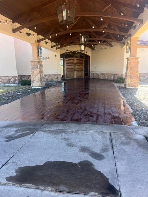 Covered entryway with arched wooden ceiling, stone pillars, and dark brick flooring leading to wooden double doors
