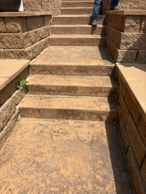 Stone staircase with wooden railings leading upward, person visible at top wearing blue jeans
